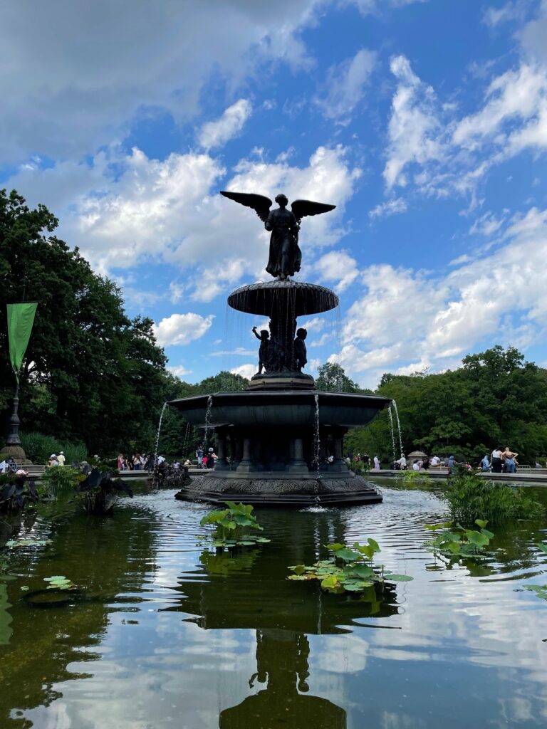 Central Park fountain surrounded by greenery and water on a bright summer day in New York City