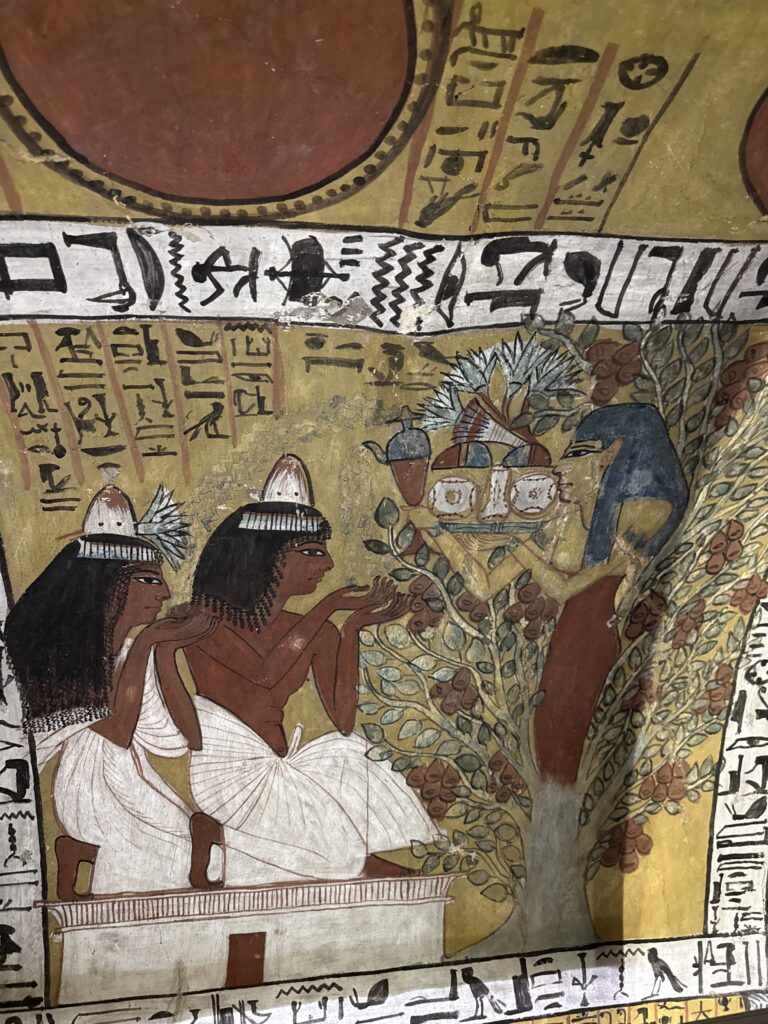 Colorful tomb painting of Egyptian figures under tree of life at Deir el-Medina