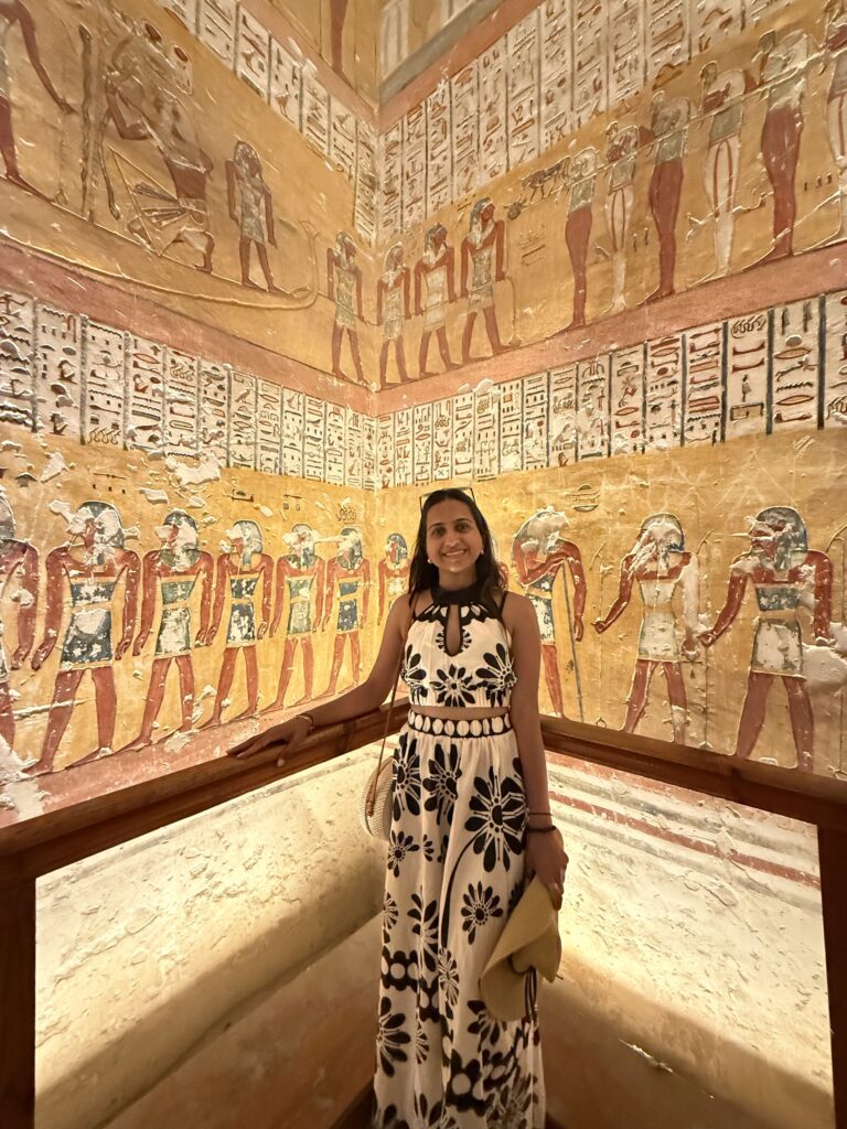 Visitor posing inside colorful painted tomb chamber at Valley of the Kings, Luxor