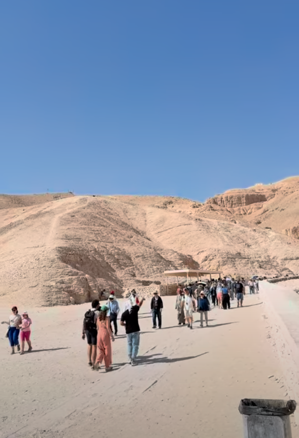 Visitors exploring Valley of the Kings on foot with tomb entrances visible in desert landscape