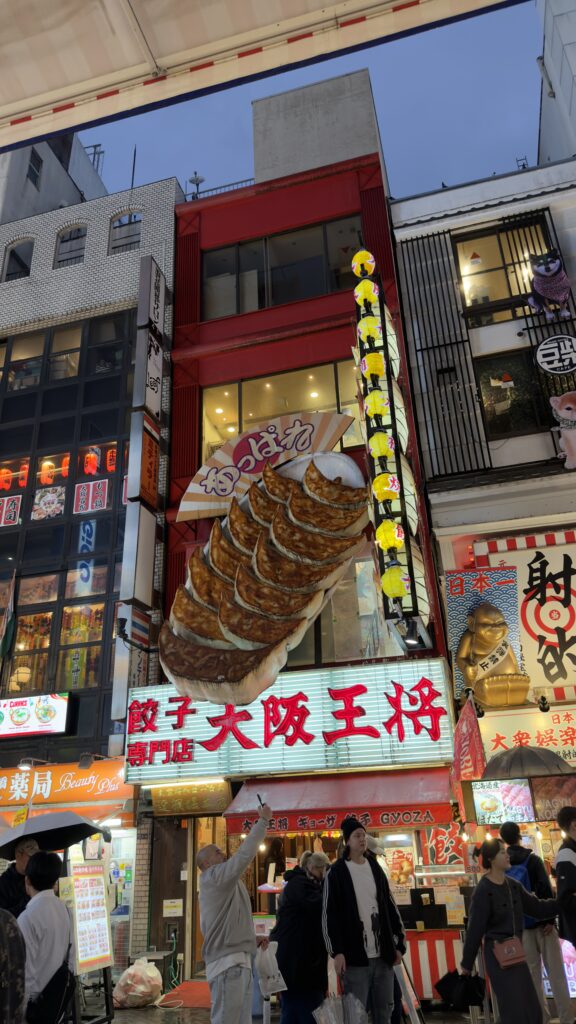 Tall building facade with the giant illuminated Osaka Osho gyoza restaurant sign and vertical banners in Dotonbori, Osaka