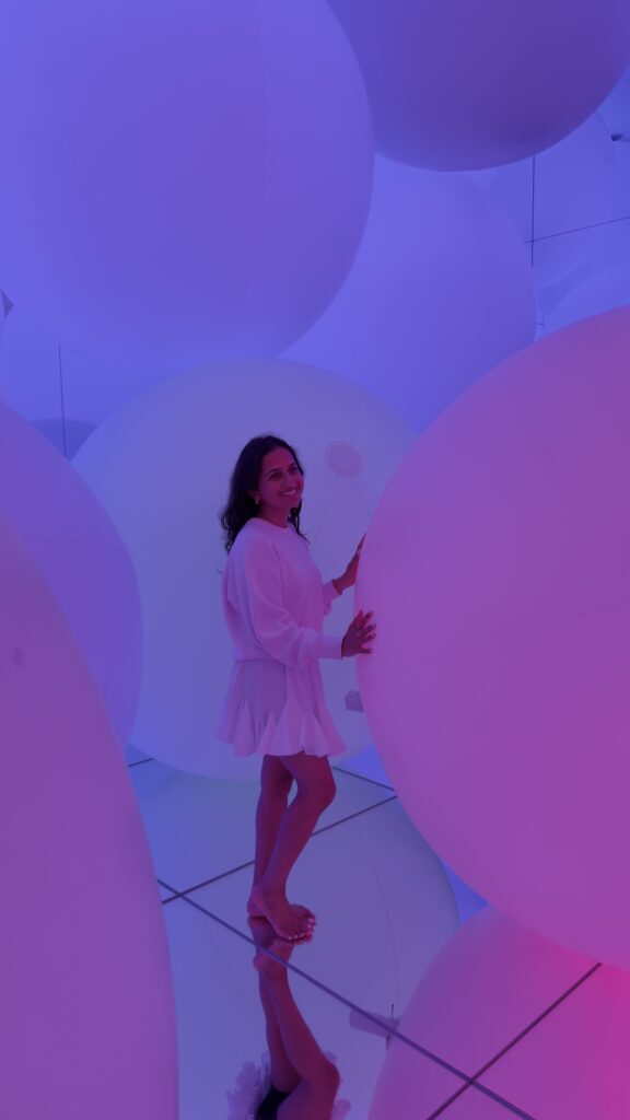 Woman in white among large floating purple and pink spheres in the immersive art installation at teamLab Planets, Tokyo