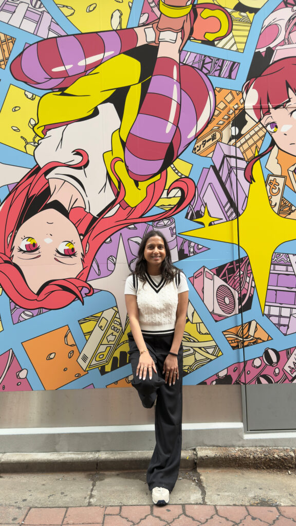 Woman posing in front of a colorful anime character mural in Akihabara, Tokyo