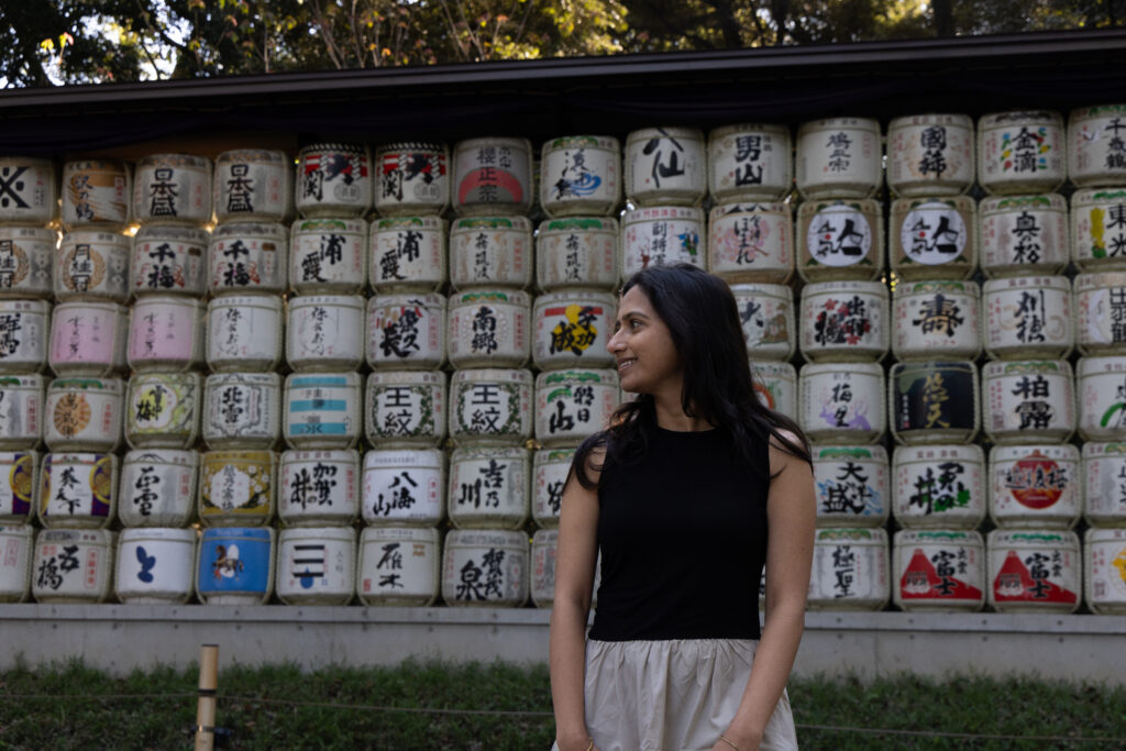 Woman standing before the stacked sake barrels at Meiji Shrine in Yoyogi Park, Tokyo